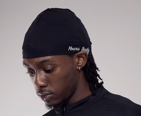 Person wearing a black head wrap with 'Yours Truly' branding on a gray background