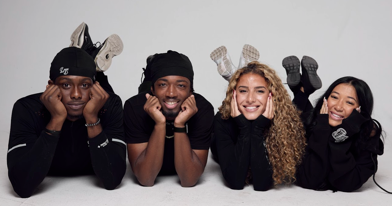 Four people posing together with a neutral background