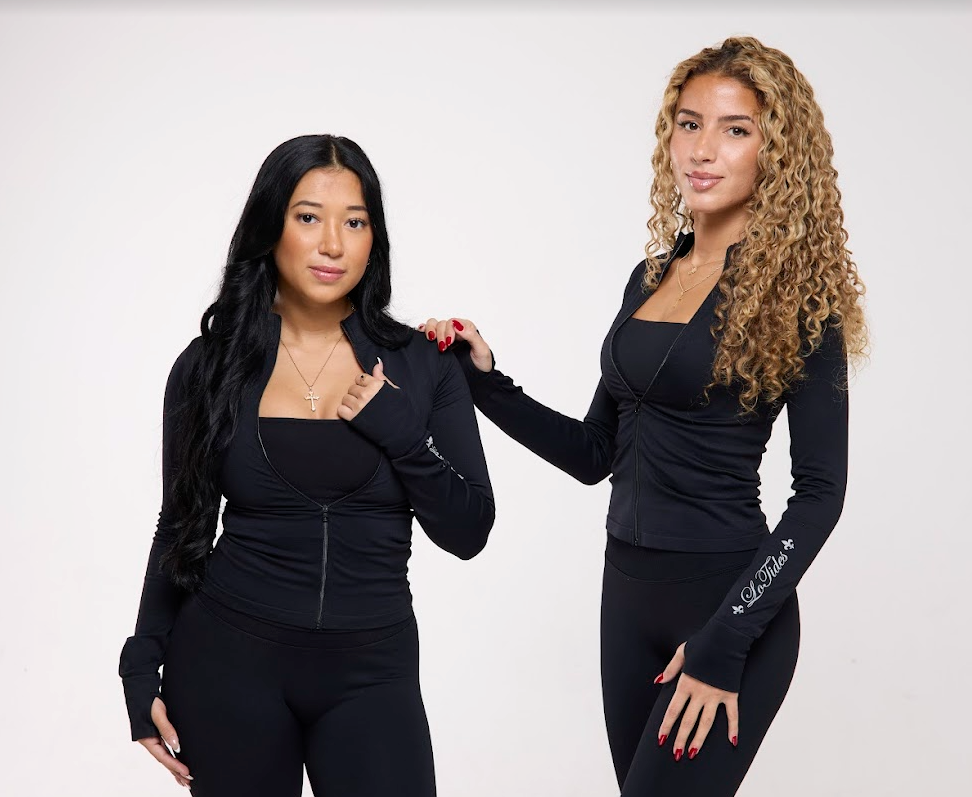 Two women wearing black outfits with visible branding on a white background