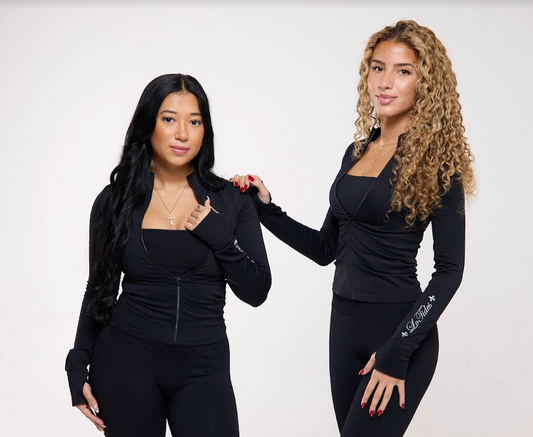 Two women wearing black outfits with visible branding on a white background